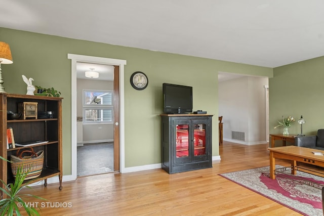 living area featuring wood finished floors, visible vents, and baseboards