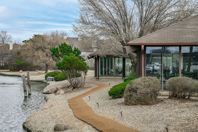 view of yard with a sunroom and a water view