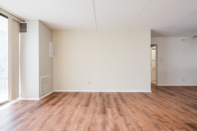 empty room featuring light wood-type flooring, visible vents, and a wealth of natural light