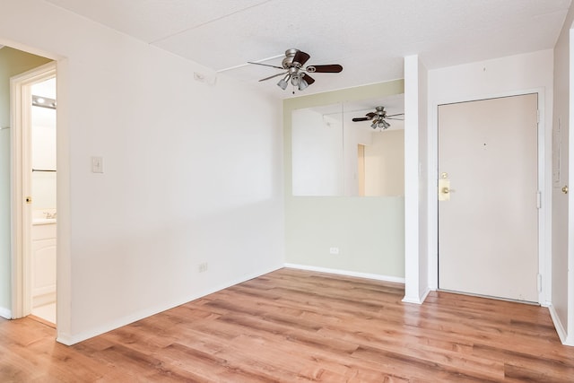 empty room featuring baseboards, a ceiling fan, and light wood-style flooring