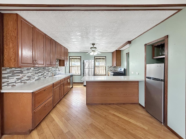 kitchen with a sink, an ornate ceiling, a ceiling fan, light countertops, and appliances with stainless steel finishes