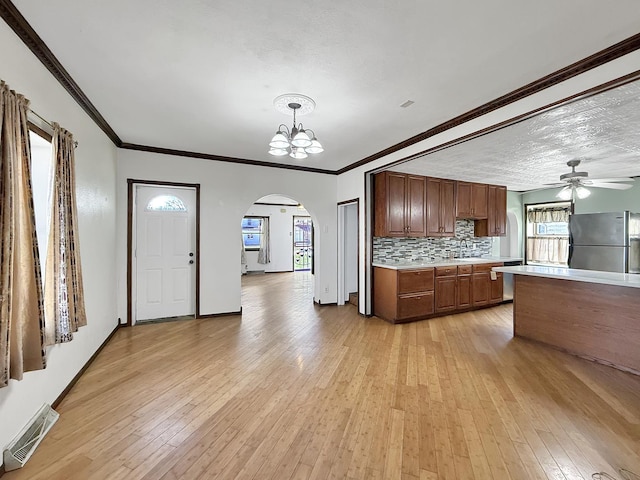 kitchen with arched walkways, visible vents, freestanding refrigerator, ceiling fan with notable chandelier, and light countertops