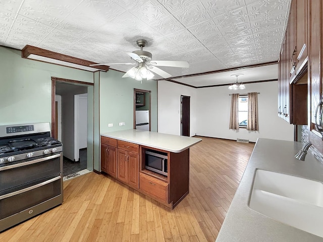 kitchen featuring a peninsula, light wood-style floors, stainless steel appliances, and a sink