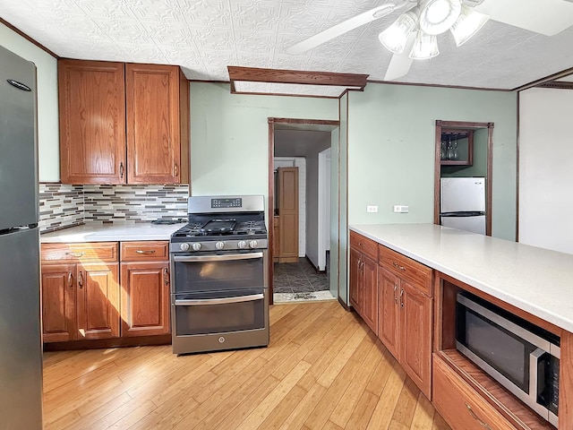 kitchen featuring a ceiling fan, stainless steel appliances, light wood finished floors, and light countertops