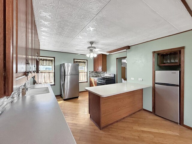 kitchen with a peninsula, a sink, appliances with stainless steel finishes, and an ornate ceiling