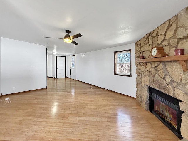unfurnished living room featuring ceiling fan, baseboards, light wood-style flooring, and a fireplace