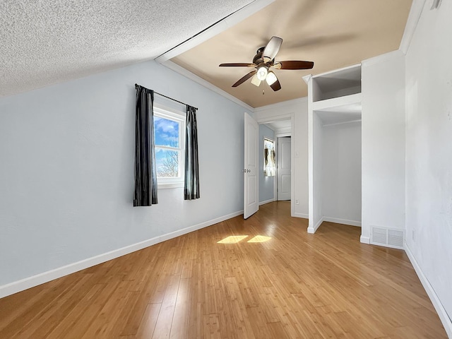 unfurnished bedroom with a ceiling fan, light wood-style floors, baseboards, lofted ceiling, and visible vents