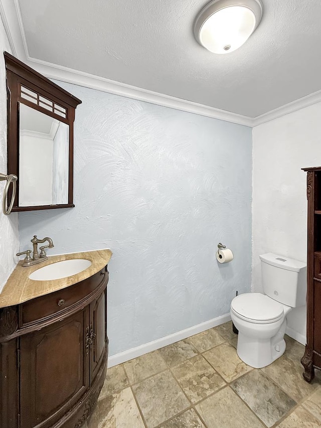 bathroom with crown molding, vanity, baseboards, toilet, and stone finish floor