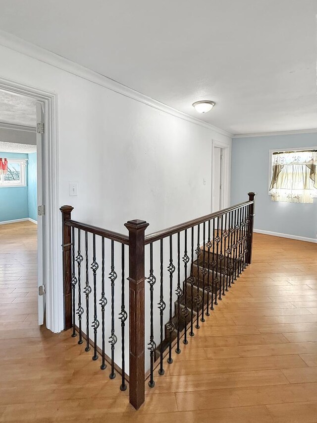 hallway featuring hardwood / wood-style flooring, a wealth of natural light, ornamental molding, and an upstairs landing