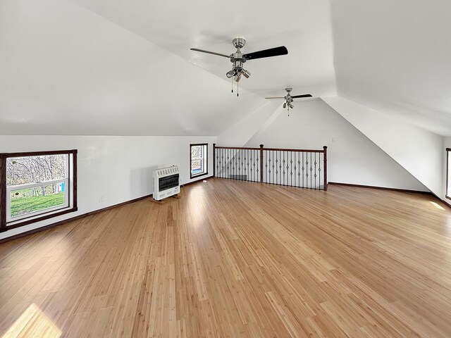 additional living space featuring light wood-type flooring, lofted ceiling, a ceiling fan, and heating unit