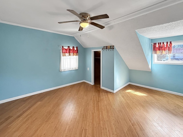 additional living space with vaulted ceiling, wood finished floors, baseboards, and ceiling fan