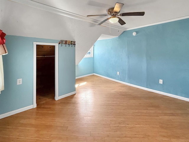 additional living space featuring baseboards, a ceiling fan, wood finished floors, and vaulted ceiling