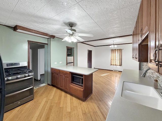 kitchen with a peninsula, light wood-type flooring, appliances with stainless steel finishes, and a sink