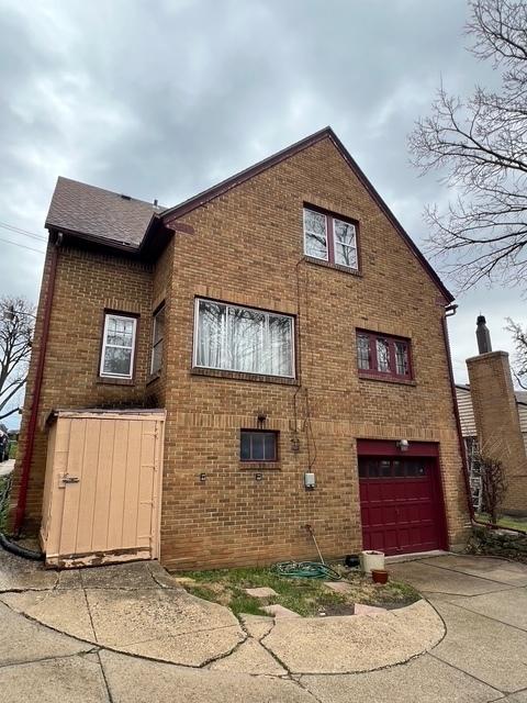 view of side of home with brick siding, an attached garage, and driveway