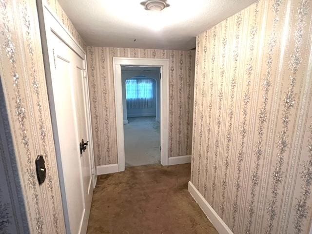 hall with wallpapered walls, carpet, and baseboards
