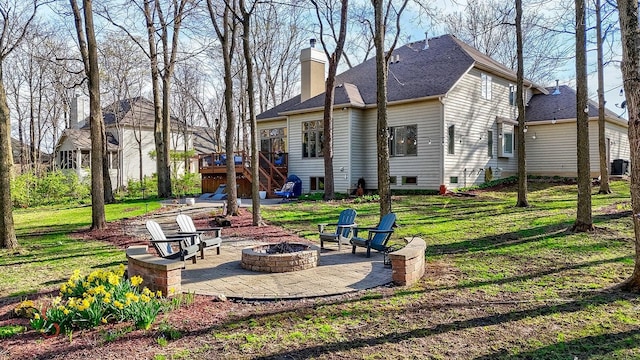 rear view of property with stairway, a chimney, a patio area, a wooden deck, and a fire pit
