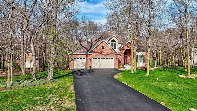 traditional home with brick siding, driveway, a front yard, and a garage