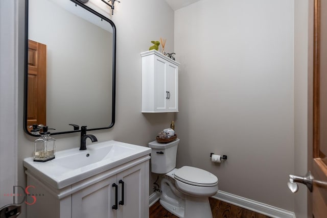 bathroom with baseboards, wood finished floors, vanity, and toilet