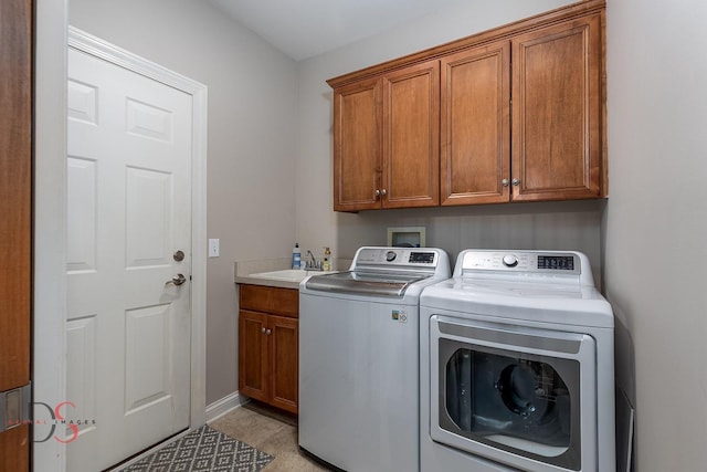 laundry room featuring washing machine and dryer, baseboards, cabinet space, and a sink