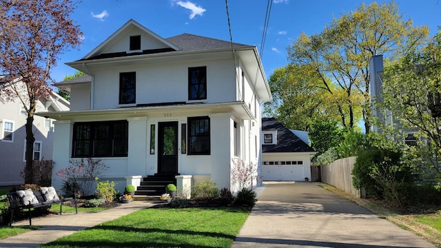 american foursquare style home with fence, a detached garage, and stucco siding