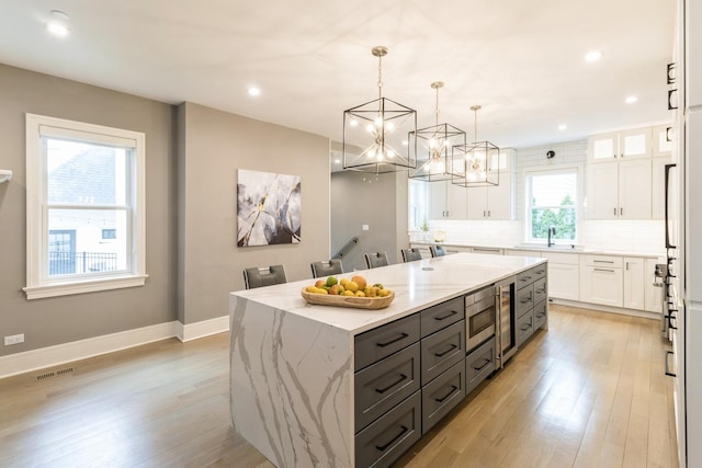 kitchen featuring a sink, white cabinetry, decorative backsplash, a kitchen island, and gray cabinets