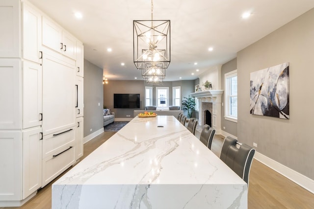 dining room featuring light wood-style flooring, a fireplace, recessed lighting, and a chandelier