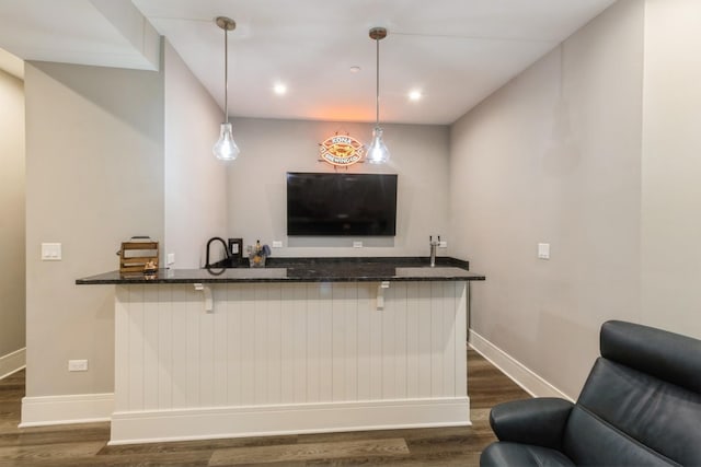 bar with baseboards, wet bar, decorative light fixtures, and dark wood-type flooring