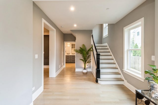 stairs featuring baseboards, plenty of natural light, and wood finished floors