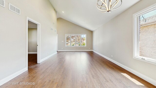 1544 N Wolf Rd, Berkeley, IL 60163 - unfurnished living room with a chandelier, wood finished floors, baseboards, and vaulted ceiling