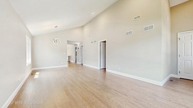 1544 N Wolf Rd, Berkeley, IL 60163 - unfurnished living room with baseboards, light wood-style floors, high vaulted ceiling, and a chandelier