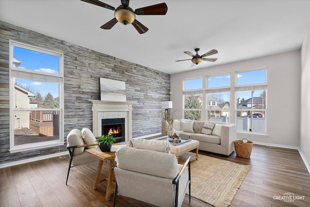 living area featuring hardwood / wood-style flooring, baseboards, a ceiling fan, and a fireplace