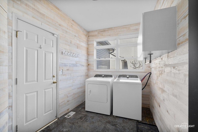 clothes washing area with wooden walls, visible vents, laundry area, and separate washer and dryer