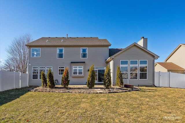 rear view of property with a lawn, a chimney, and a fenced backyard