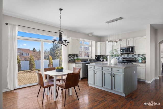 kitchen featuring stainless steel appliances, backsplash, a sink, and a chandelier