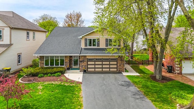 view of front of house featuring aphalt driveway, fence, a front yard, brick siding, and an attached garage
