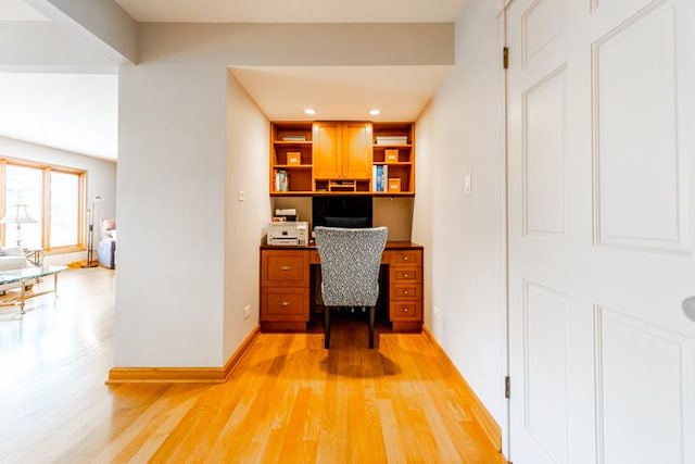 office with light wood-style floors, baseboards, and built in desk