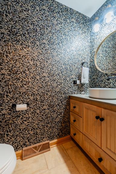 half bath featuring vanity, toilet, wallpapered walls, baseboards, and visible vents