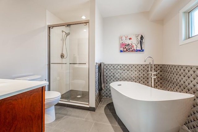full bathroom featuring a freestanding tub, tile walls, tile patterned flooring, a shower stall, and toilet