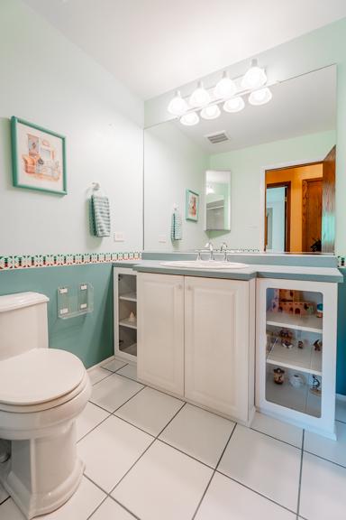 half bath featuring vanity, tile patterned flooring, visible vents, and toilet