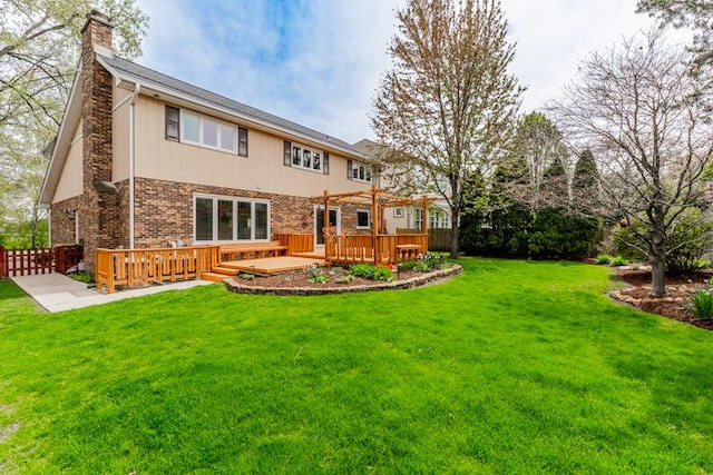 back of property featuring a chimney, a wooden deck, brick siding, fence, and a yard