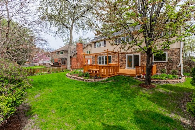 rear view of property featuring fence, brick siding, a deck, a chimney, and a yard
