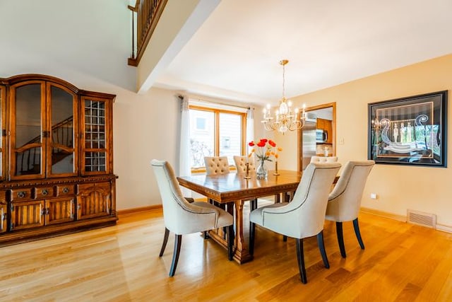 dining area featuring a chandelier, baseboards, visible vents, and light wood-style floors