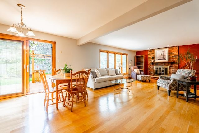 dining room with a brick fireplace, wood finished floors, and a notable chandelier
