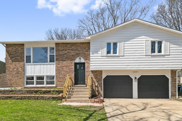 raised ranch featuring concrete driveway, brick siding, and a garage