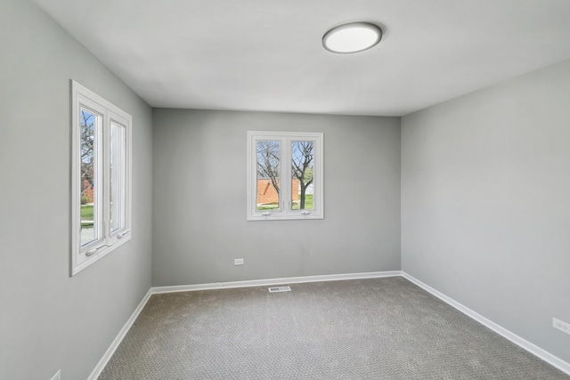 carpeted spare room featuring visible vents and baseboards