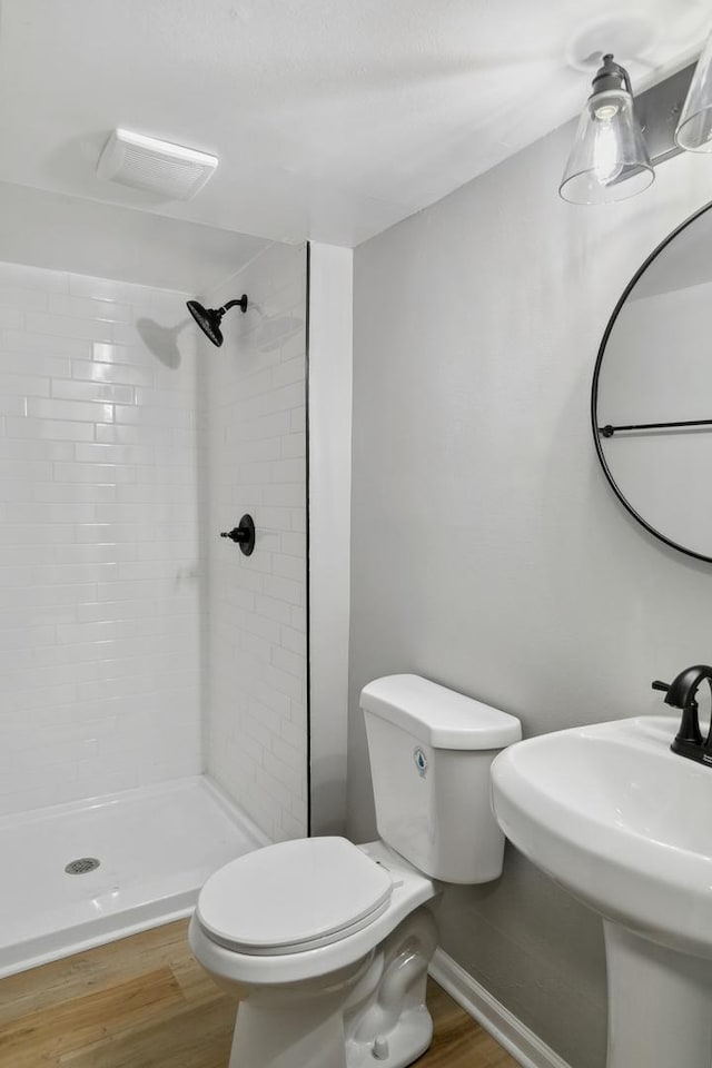 full bath with toilet, a stall shower, a sink, and wood finished floors