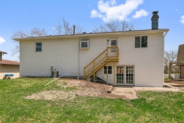 rear view of property featuring a chimney, central air condition unit, and a lawn