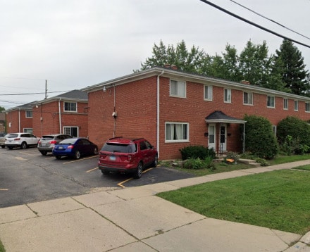 view of front of home with uncovered parking, brick siding, and a front yard