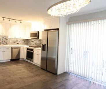kitchen featuring dark wood-style flooring, tasteful backsplash, white cabinetry, light countertops, and appliances with stainless steel finishes
