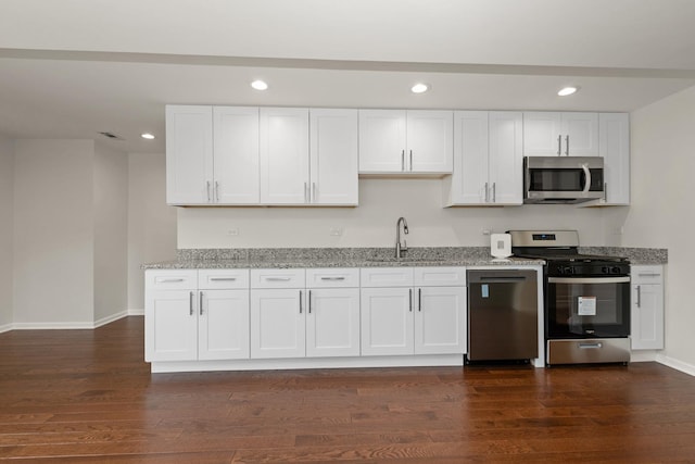 kitchen featuring stainless steel appliances, a sink, recessed lighting, white cabinets, and light stone counters